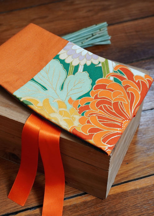 Ravissante ceinture de style obi, cet accessoire tendance, pièce incontournable de la garde-robe met la taille en valeur et affine la silhouette. Les côtés sont orange brulé, le tissu central de kimono représente une belle fleur de chrysanthème orange. Le ruban est orange vif.