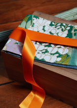 Load image into Gallery viewer, Ravissante ceinture de style obi, cet accessoire tendance, pièce incontournable de la garde-robe met la taille en valeur et affine la silhouette.  Les côtés sont vert jade, le tissu central est un kimono en soie avec des fleurs mauves, des glycines et des feuilles. Le ruban est orange mandarine.

