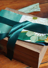 Load image into Gallery viewer, Les côtés sont vert jade, le tissu central est un kimono en soie avec des fleurs blanches, oranges et dorées et des feuilles. Le ruban est vert bouteille.
