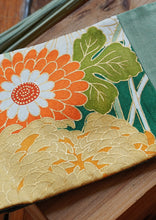 Load image into Gallery viewer, Les côtés sont vert jade, le tissu central est un kimono en soie avec des fleurs blanches, oranges et dorées et des feuilles. Le ruban est vert bouteille.
