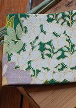 Load image into Gallery viewer, Ravissante ceinture de style obi, cet accessoire tendance, pièce incontournable de la garde-robe met la taille en valeur et affine la silhouette.  Les côtés sont vert jade, le tissu central est un kimono en soie avec des fleurs mauves, des glycines et des feuilles. Le ruban est orange mandarine.

